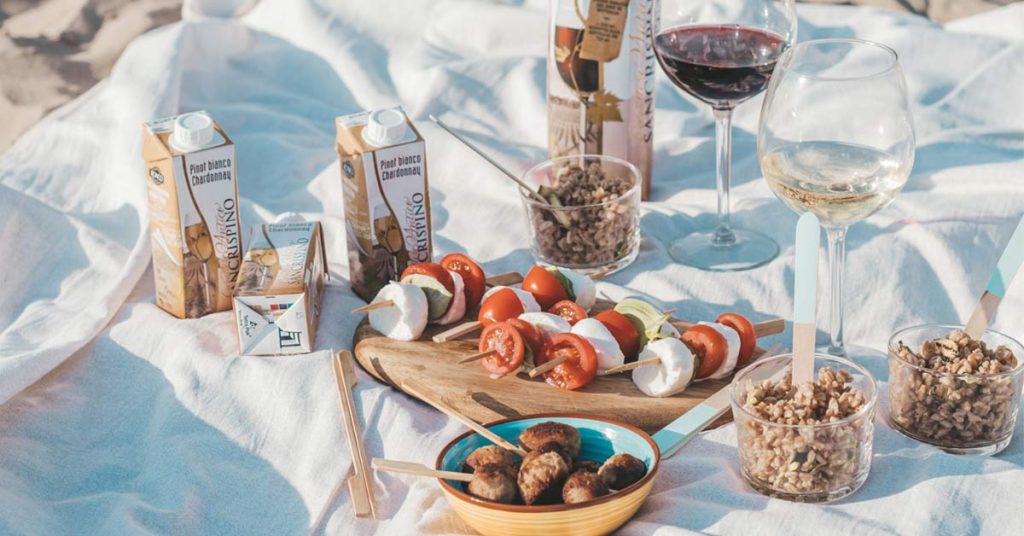 picnic sulla spiaggia con bicchieri di vino e cibo